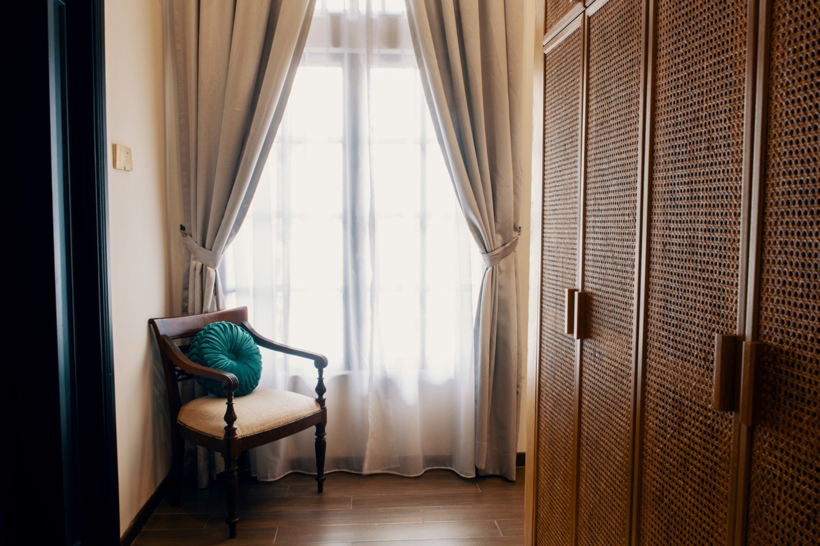 Cozy seating area with natural light in The Agam’s private suite, featuring elegant decor and wooden wardrobe.