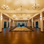 Spacious Upper Hall at The Agam, featuring chandeliers, high ceilings, and elegant flooring, perfect for weddings and large events.