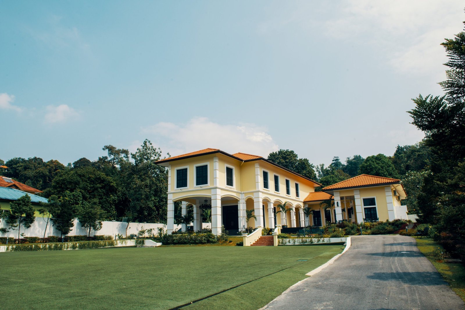 The Agam venue with colonial-inspired architecture, surrounded by a spacious outdoor front lawn and lush greenery.