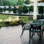 Outdoor seating area on the garden deck at The Agam, overlooking the spacious front lawn and lush greenery.