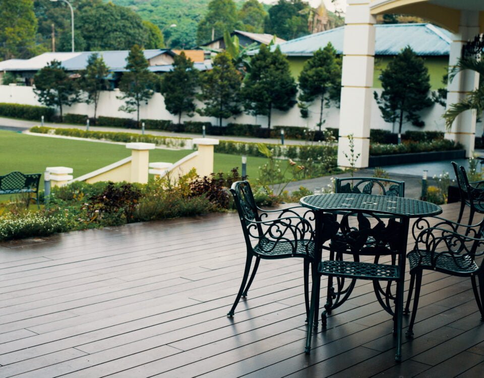 Outdoor seating area on the garden deck at The Agam, overlooking the spacious front lawn and lush greenery.