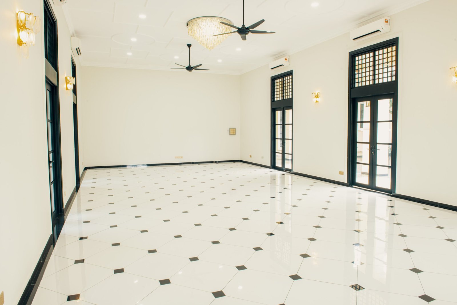 Elegant Grand Hall at The Agam with chandeliers, high ceilings, and large windows, offering a spacious venue for events and receptions.