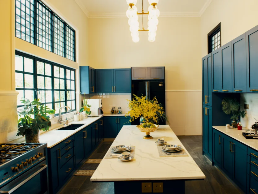 Spacious, modern kitchen at The Agam with blue cabinetry, marble countertops, and elegant lighting, perfect for catering events.