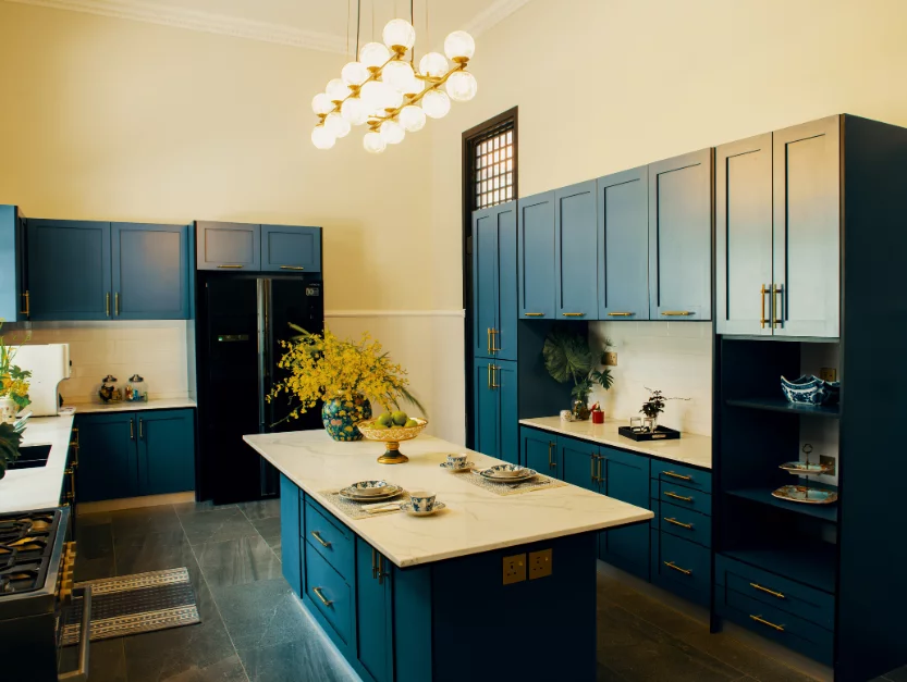 Luxurious kitchen at The Agam featuring blue cabinets, marble island, and elegant lighting, ideal for event catering and private dining.