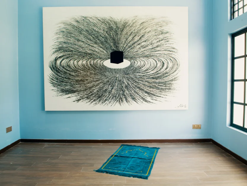 Prayer room at The Agam, featuring a modern abstract artwork and prayer mat, offering a serene space for reflection.
