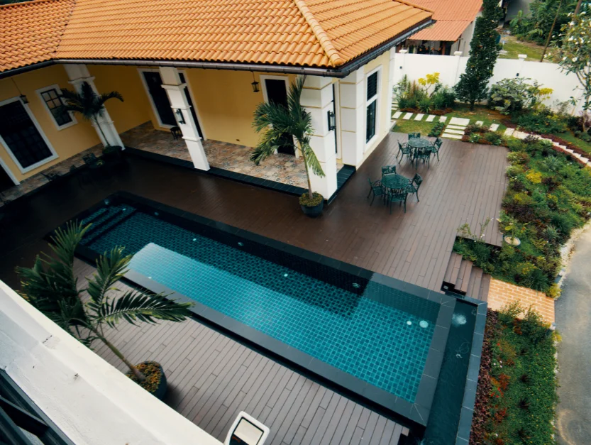 Elegant swimming pool area at The Agam, surrounded by a deck and garden, perfect for outdoor events and relaxation.